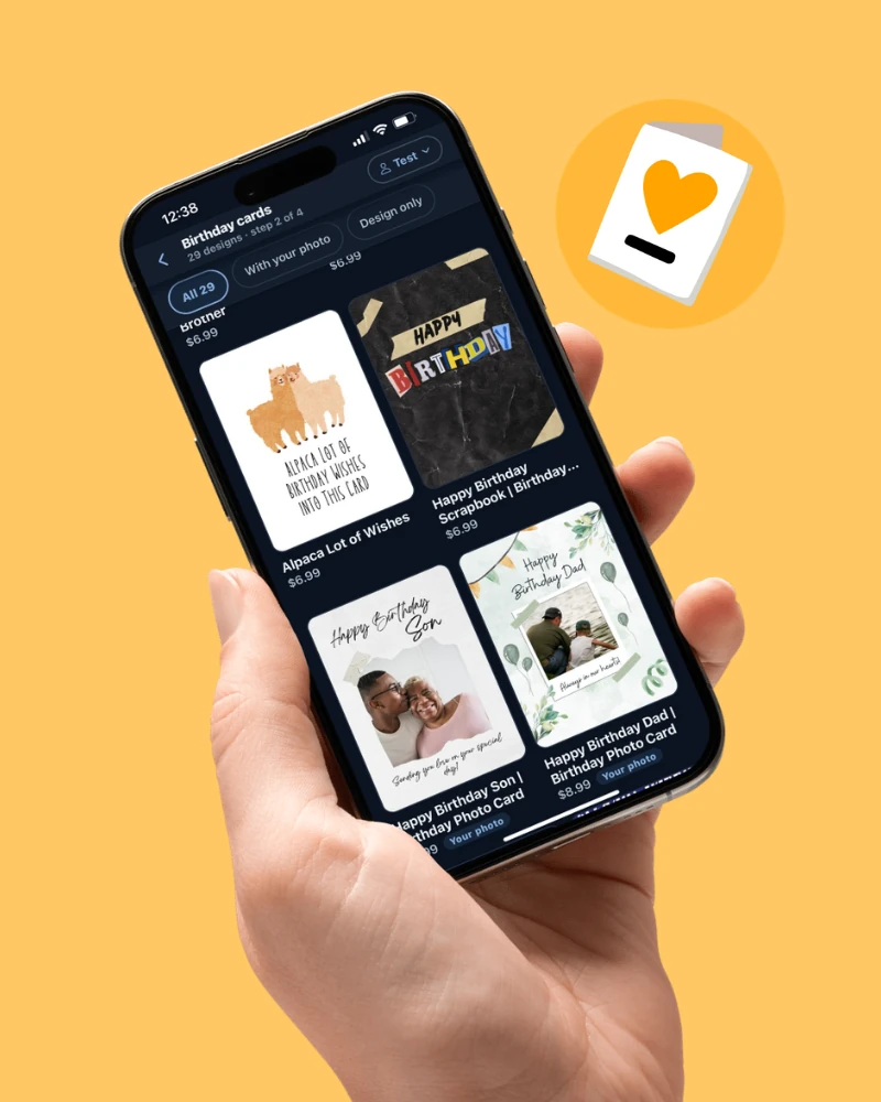 A hand holding a phone with the Pelipost app open to the birthday card designs, ready to send to an incarcerated loved one